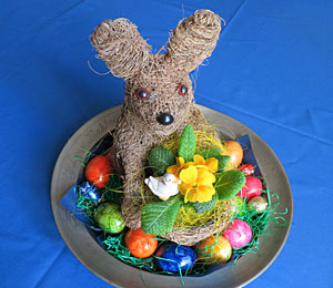 Osterhase auf Teller mit Hühner- und Schokoeiern.